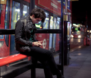 146473315-young-man-checks-phone-at-bus-stop-gettyimages